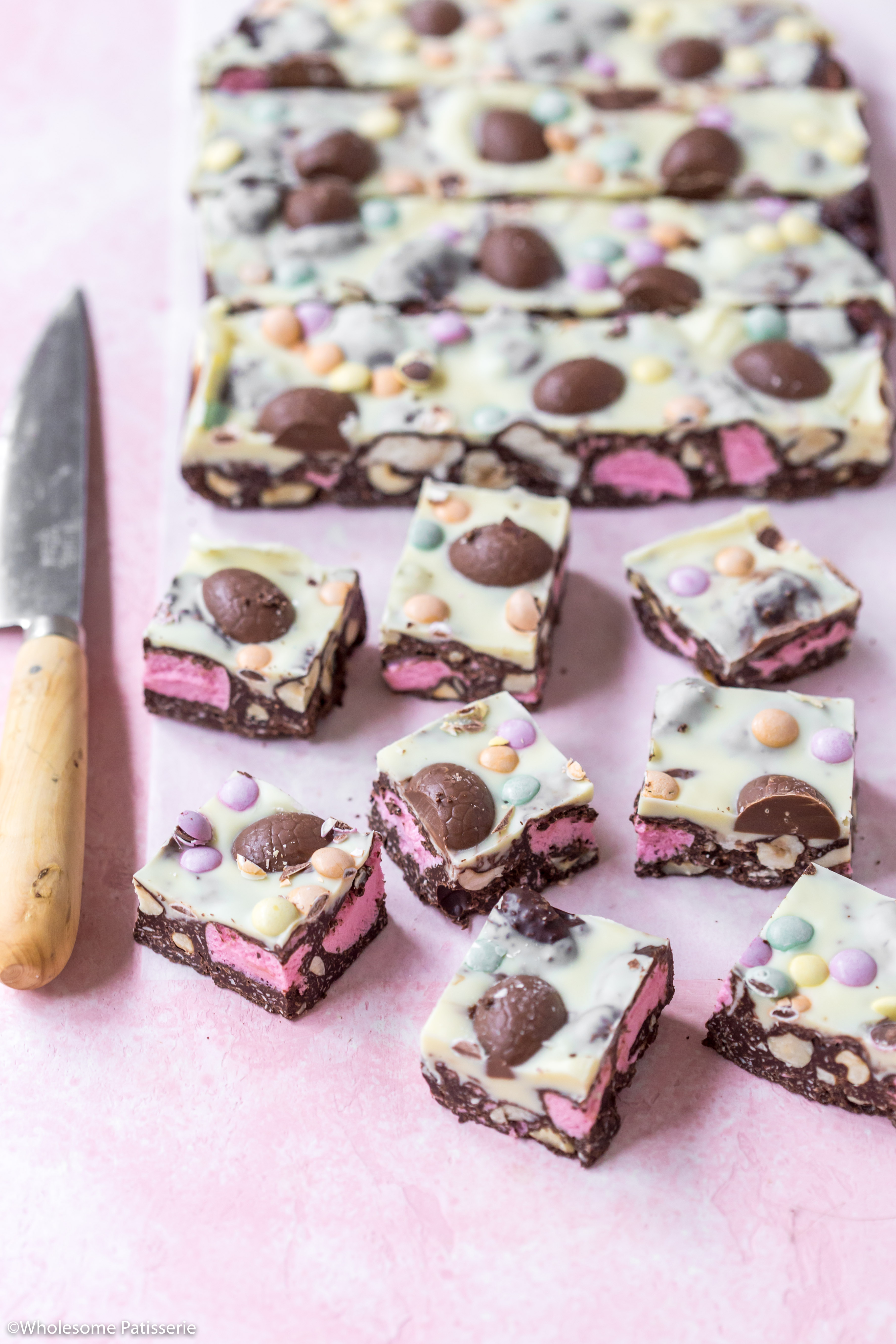 Easter rocky road sliced into squares and displayed on pink backdrop next to decorative knife.