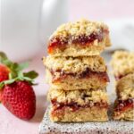The strawberry crumble bars stacked on top of each other ready to take a bar and enjoy.
