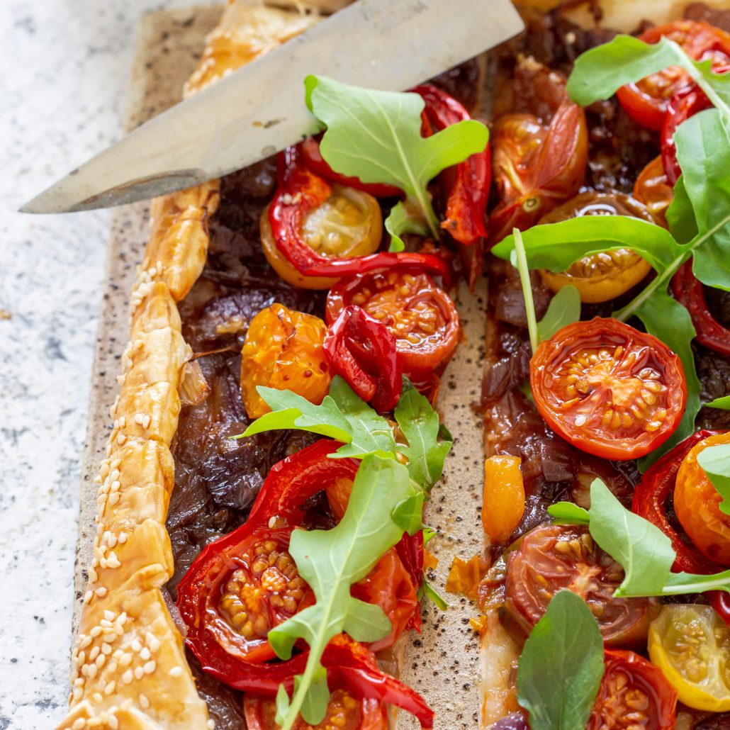 Caramelised Onion Tomato & Capsicum Tart! A fabulous tart to serve over the festive season! The caramelised onions add depth of flavour whilst the cherry tomatoes and capsicum add freshness and texture! Topped with rocket and basil creating a delicious homemade pastry tart everyone will enjoy!