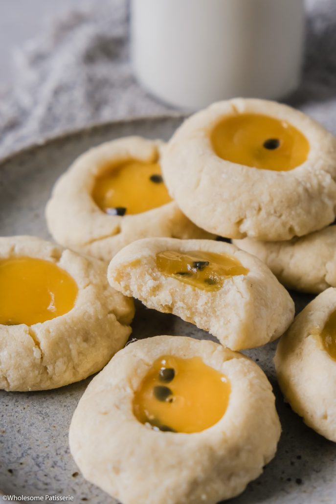 Passionfruit Curd Thumbprint Cookies! Melt in your mouth shortbread cookies filled with luxurious and sweet passionfruit curd! These soft cookies are an absolute treat. The shortbread cookie dough is easy done in one mixing bowl then formed into your thumbprints. Fill them up with either store bought or homemade passionfruit curd. Bake to perfection and you’re ready to indulge! 