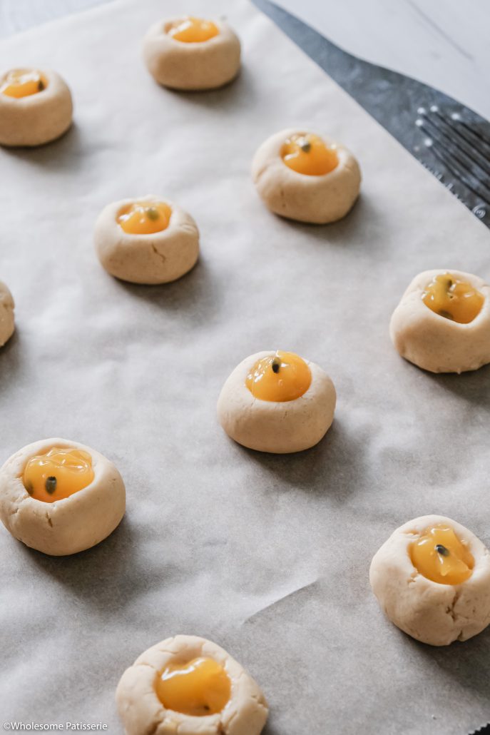 Passionfruit Curd Thumbprint Cookies! Melt in your mouth shortbread cookies filled with luxurious and sweet passionfruit curd! These soft cookies are an absolute treat. The shortbread cookie dough is easy done in one mixing bowl then formed into your thumbprints. Fill them up with either store bought or homemade passionfruit curd. Bake to perfection and you’re ready to indulge!
