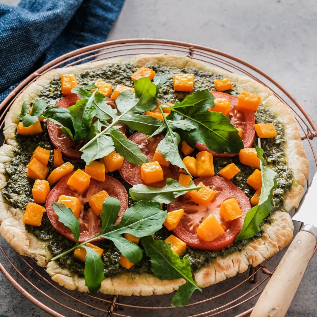 Pesto & Roasted Pumpkin, Tomato Flat Bread! This easy 5-ingredient flat bread whips up in no time, then it’s ready for it’s toppings! First spread with a spinach and basil pesto, your choice of either store-bought or homemade. I recommend using my Pesto Recipe and halving it, making it the perfect quantity to spread on your flat bread. Then you’ll top it with fresh slices of tomato, roasted pumpkin cubed and fresh rocket!