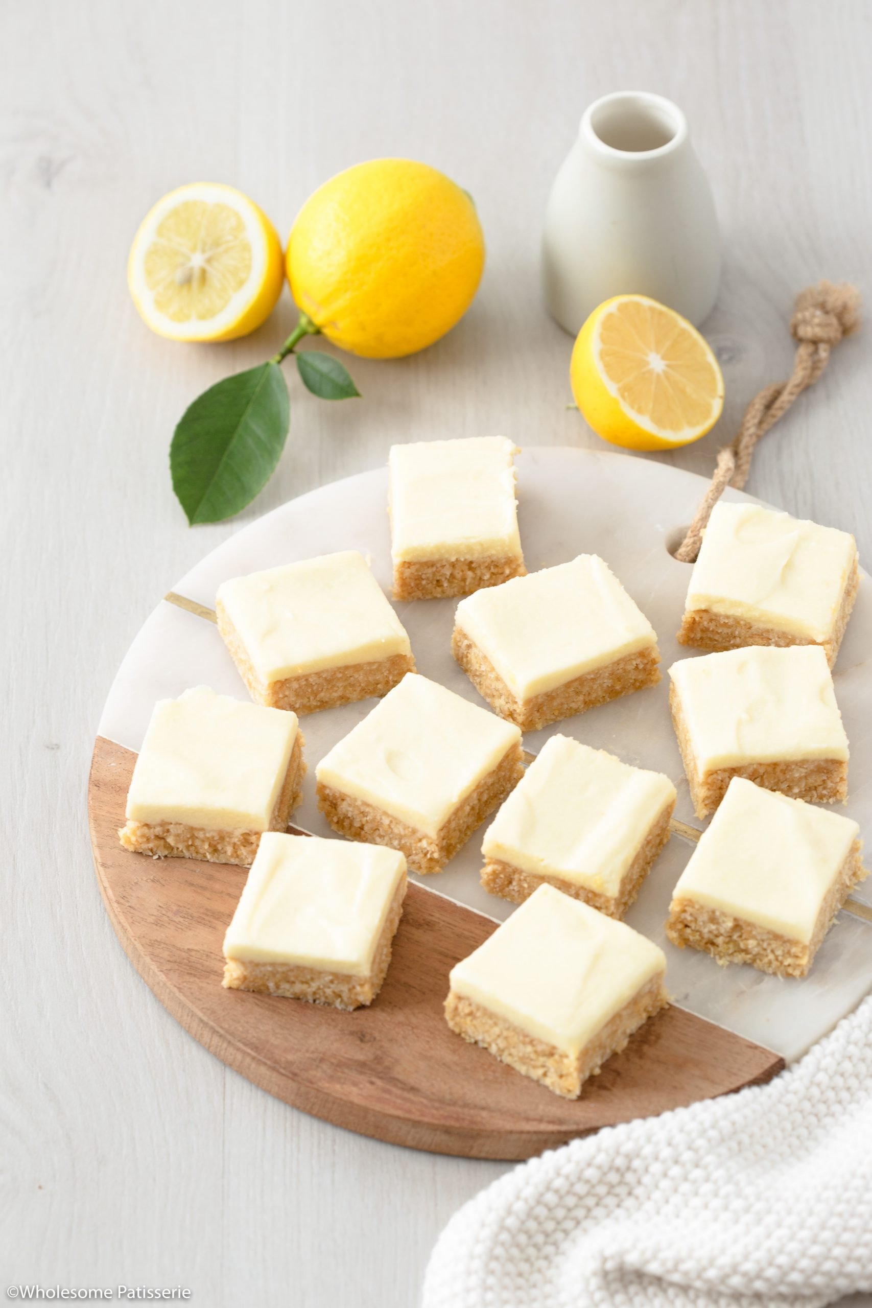 Overhead image of the cut up easy lemon coconut slice on a serving platter ready to enjoy with fresh sliced lemons 
