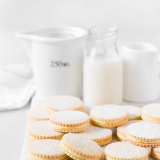 Orange cream biscuits laid out on marble platter with milk jugs behind