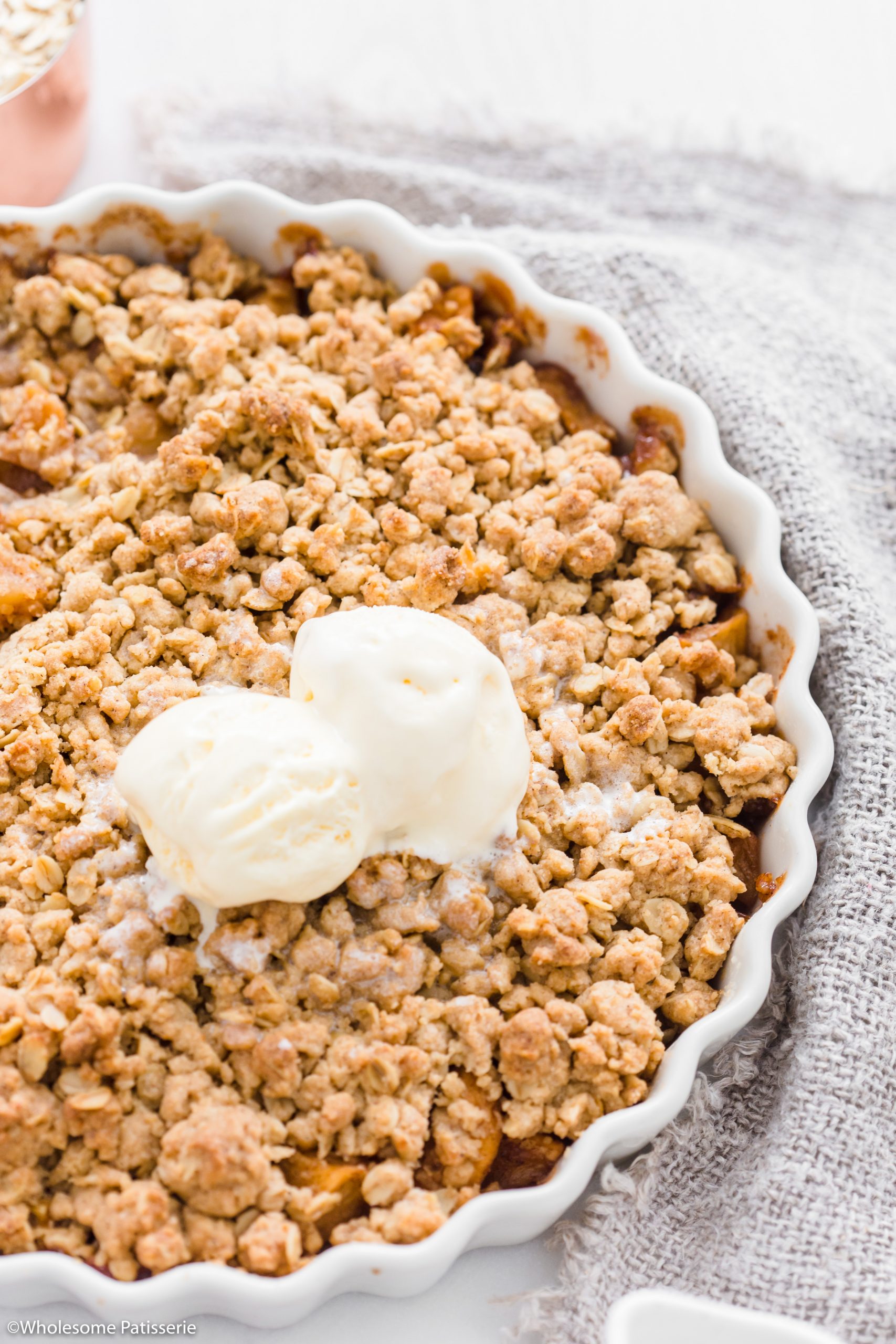 close up view of the crumble topping with scoops of vanilla ice cream to serve. 
