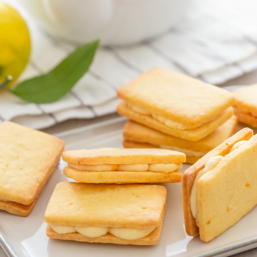 Lemon Cream Shortbread Biscuits! Two layers of melt in your mouth shortbread biscuits filled with a zesty lemon cream. The biscuit dough is created in one bowl then cut into small rectangles and baked. The lemon filling is made with four ingredients and one bowl. Sandwich the biscuits together to create your scrumptious lemon cream shortbread biscuits.