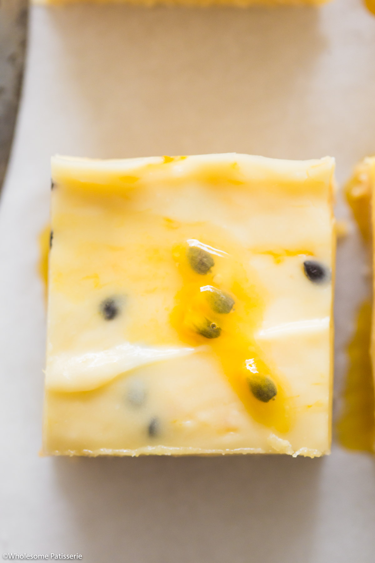 Close up overhead of one passionfruit square with fresh passionfruit pulp on top.