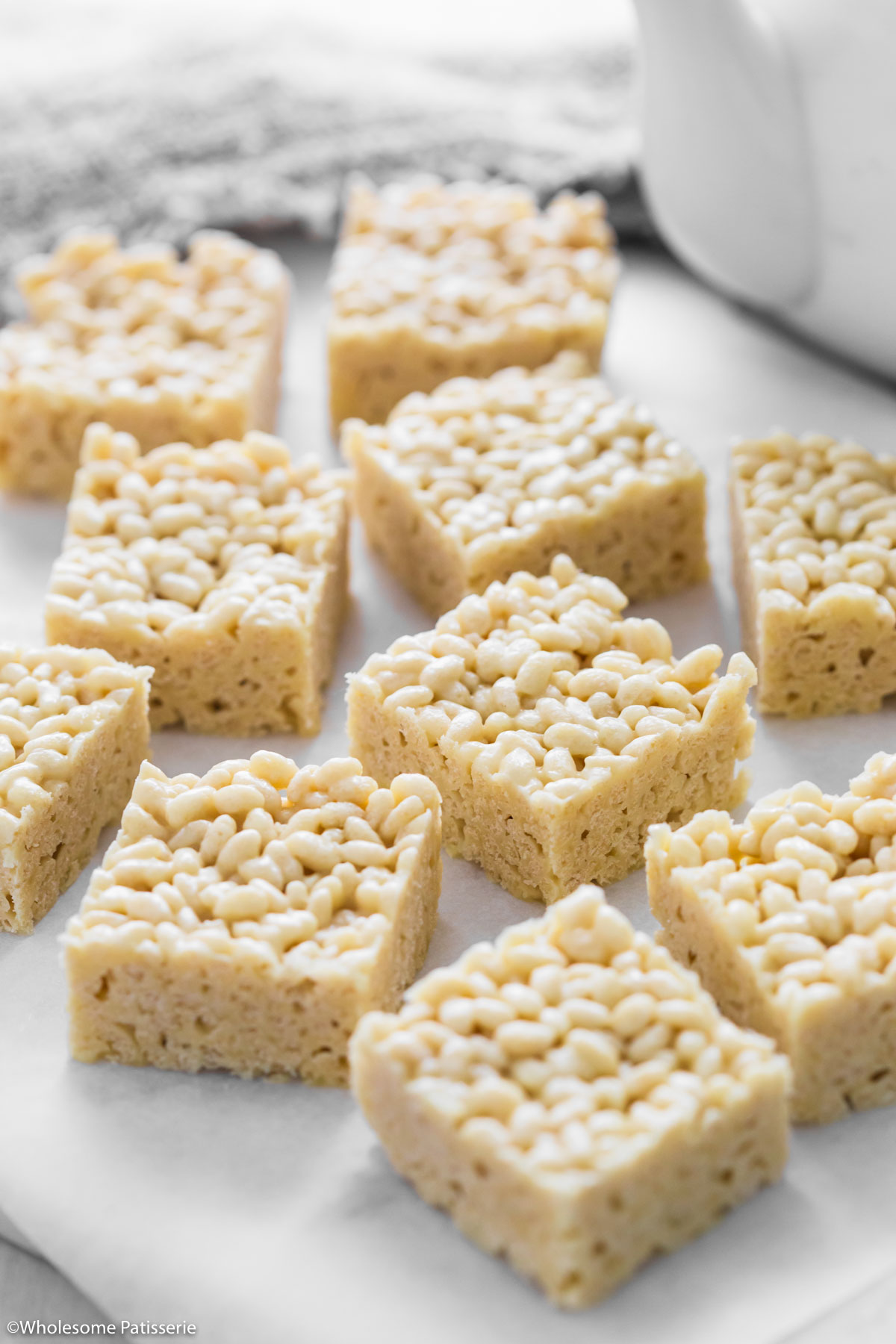 Rice bubble slice with white chocolate sliced into squares sitting on white platter.