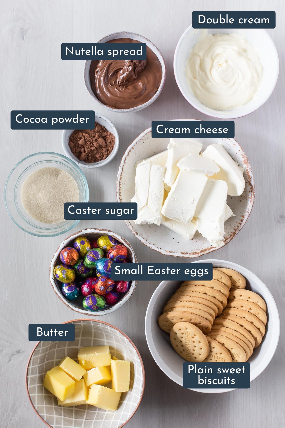 Ingredients to make Easter Nutella No Bake Cheesecake is cream cheese block, plain sweet biscuits, butter, cocoa powder, small easter eggs, double cream, caster sugar and nutella.