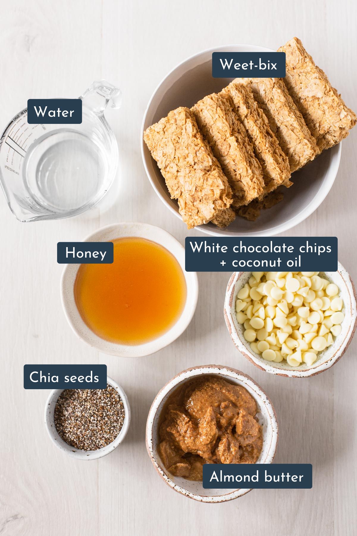 Ingredients needed to make Weetbix slice is Weetbix, water, chia seeds, almond butter, honey, white chocolate chips and coconut oil.