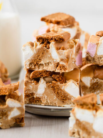 Biscoff rocky road cut into squares stacked together on plate.