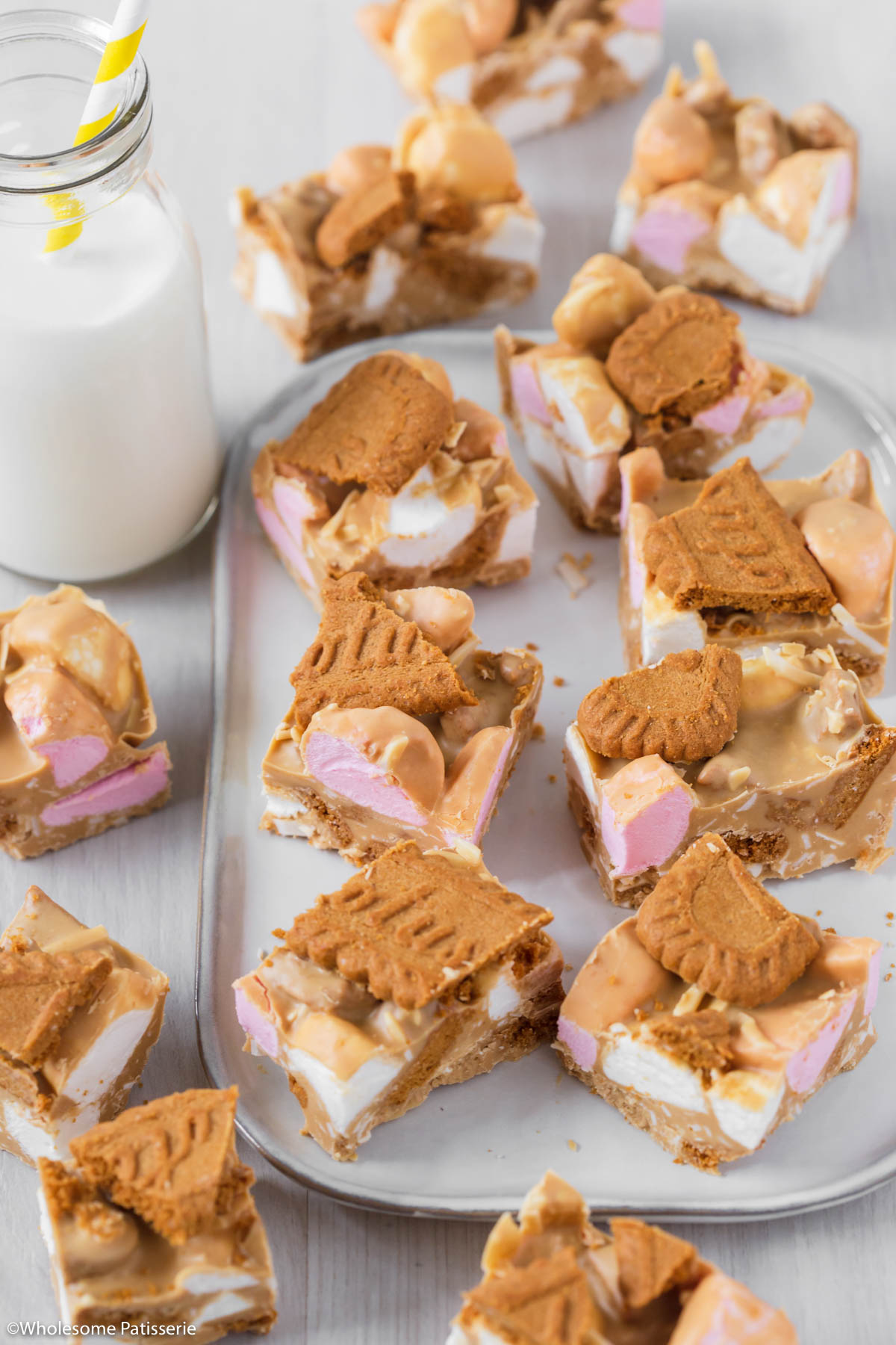Biscoff rocky road cut into squares all sitting on a serving platter next to glass of milk.