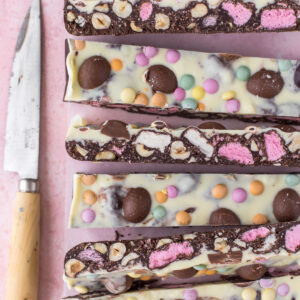 Easter Rocky Road sliced and displayed on pink backdrop next to knife.