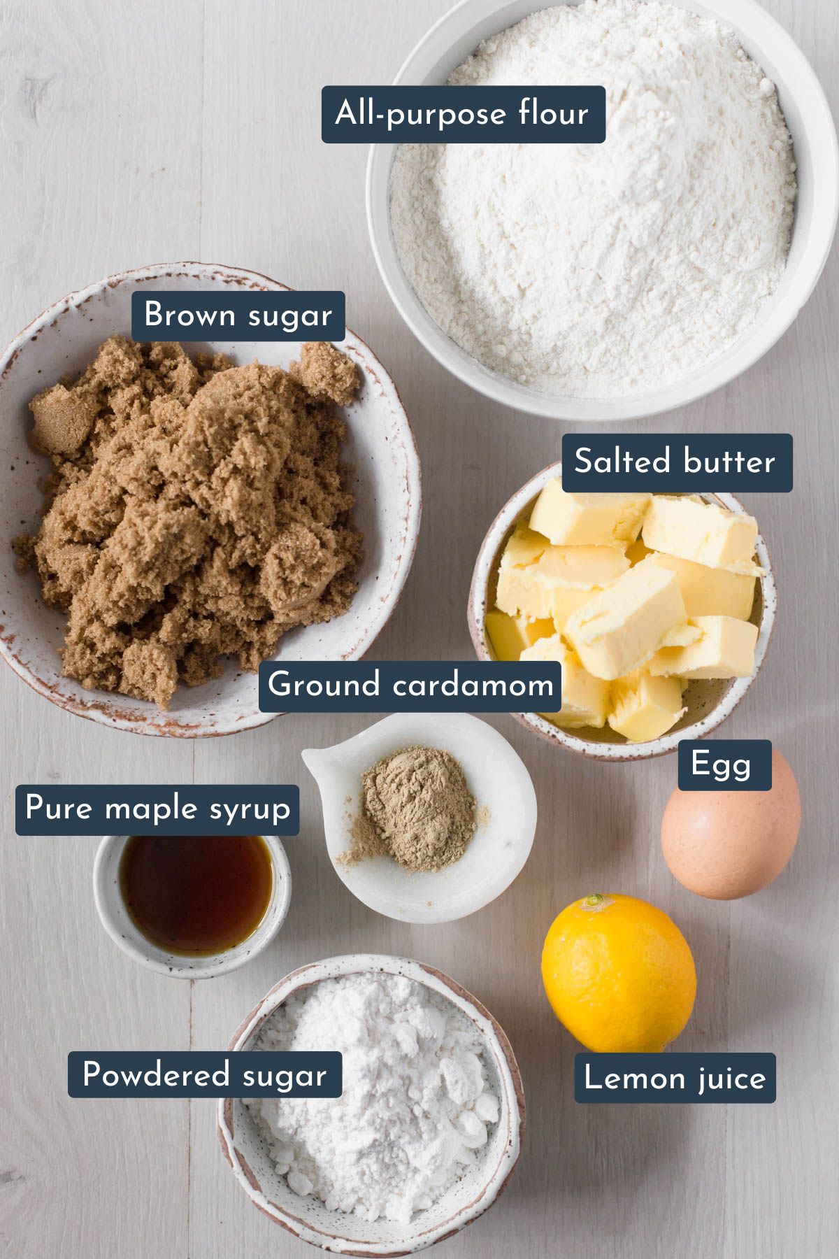Ingredients to make cardamom cookies is all-purpose flour, brown sugar, ground cardamom, egg, salted butter, maple syrup, powdered sugar and lemon juice.
