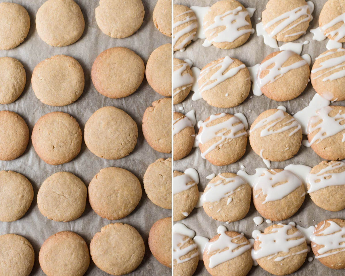 Baked cardamom cookies on a lined baking tray being drizzled with the lemon icing