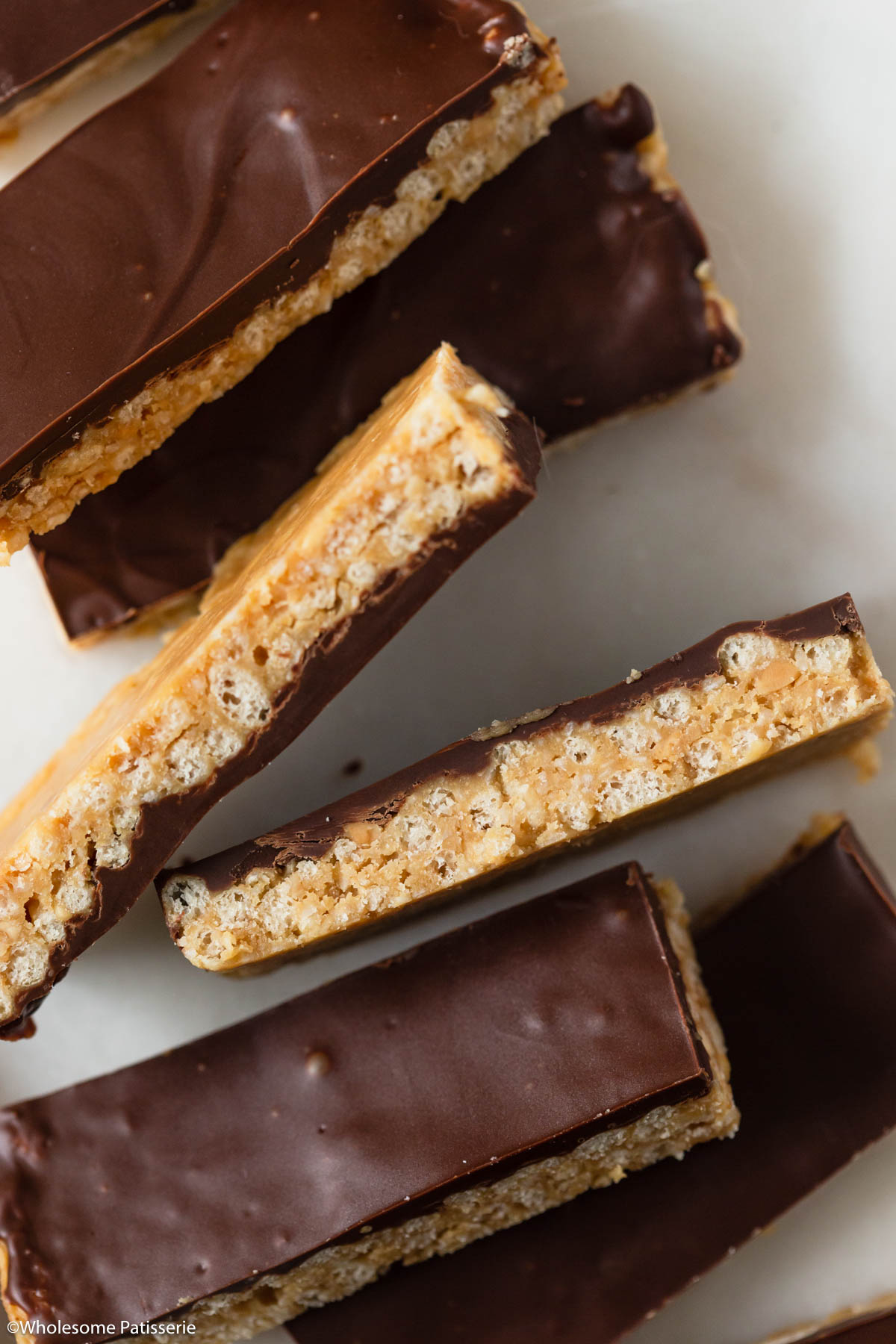 Peanut butter crunch bars displayed on white marble platter.
