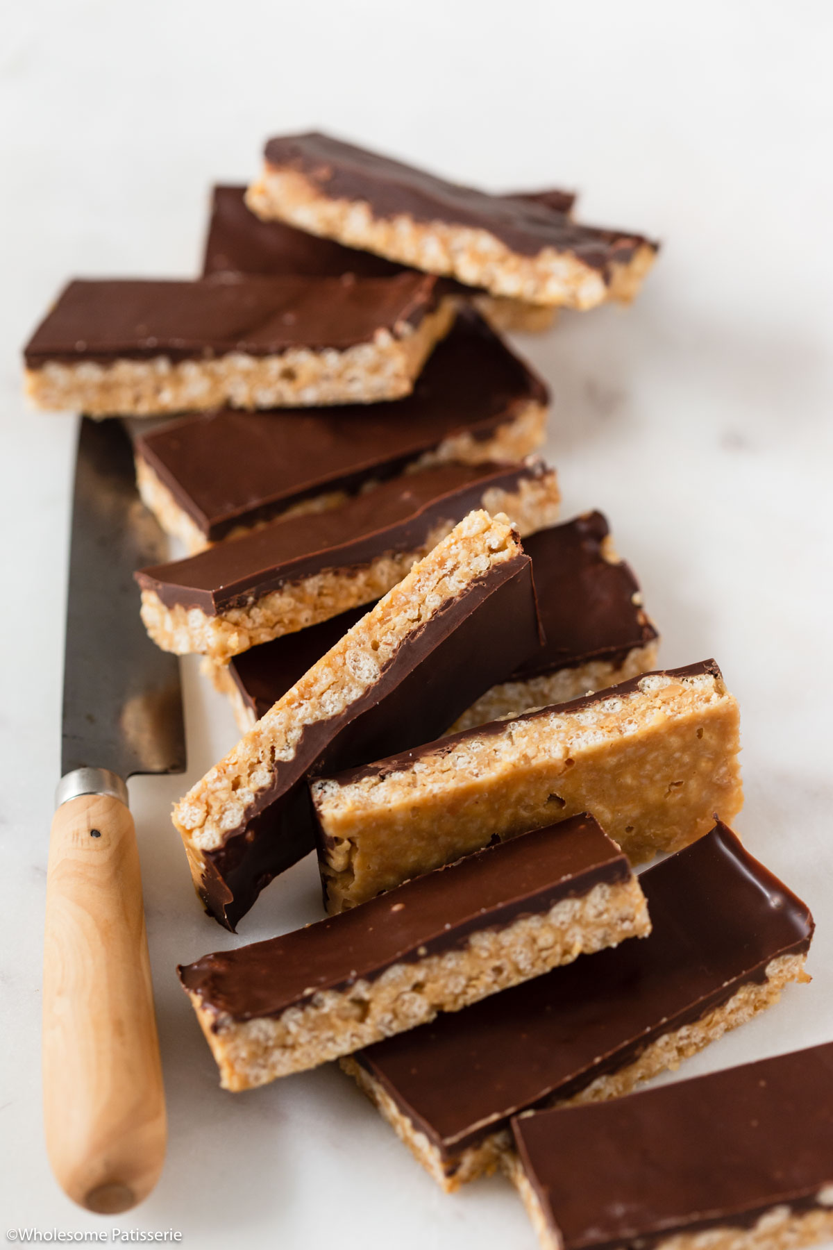 Crunch bars cut into linger bars and stacked together on a platter next to a decorative knife.