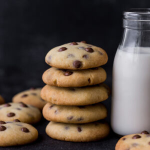 Sweetened Condensed milk cookies stacked together next to a glass of milk