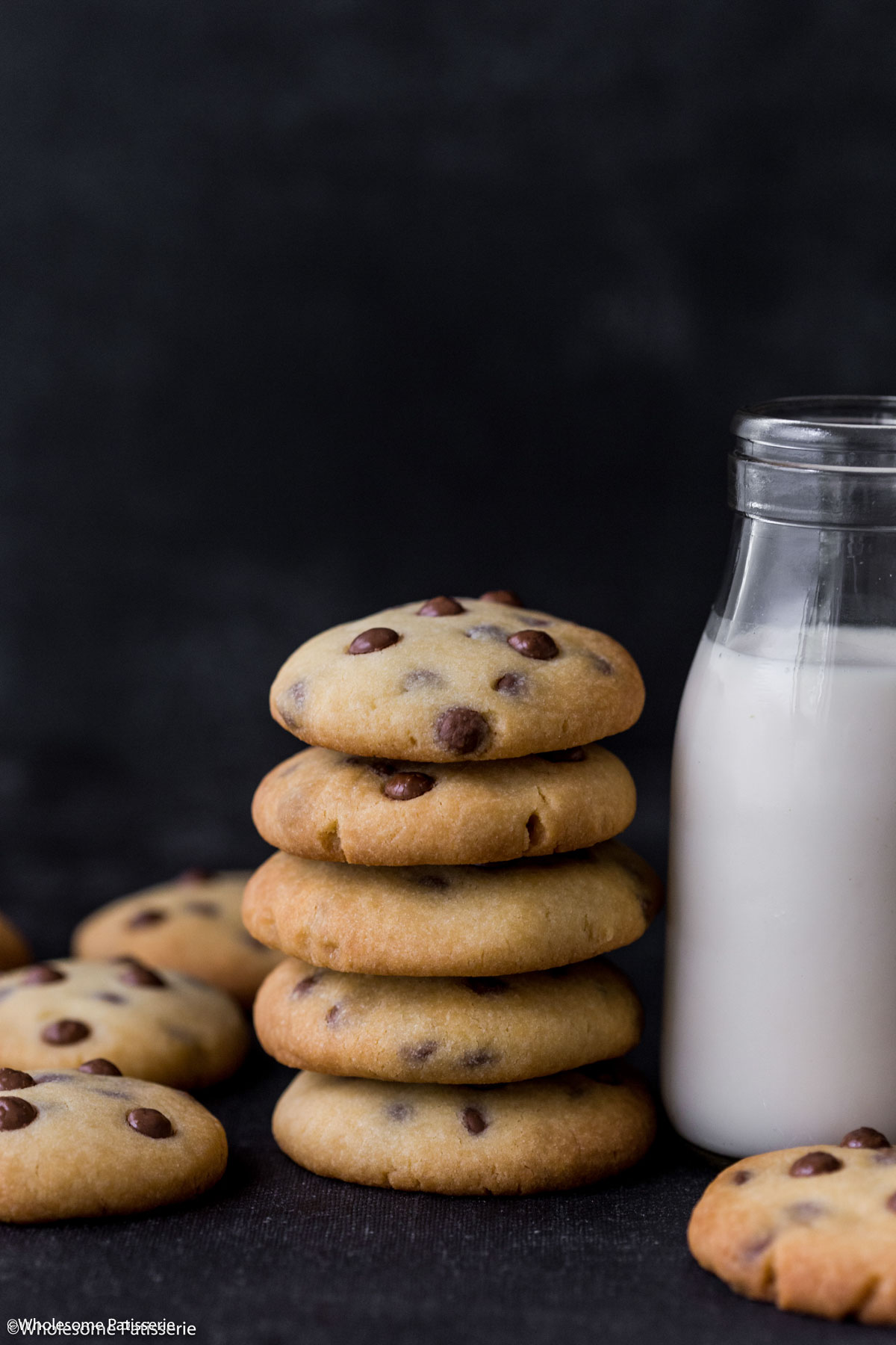 Condensed milk cookies stacked together next to a glass of milk