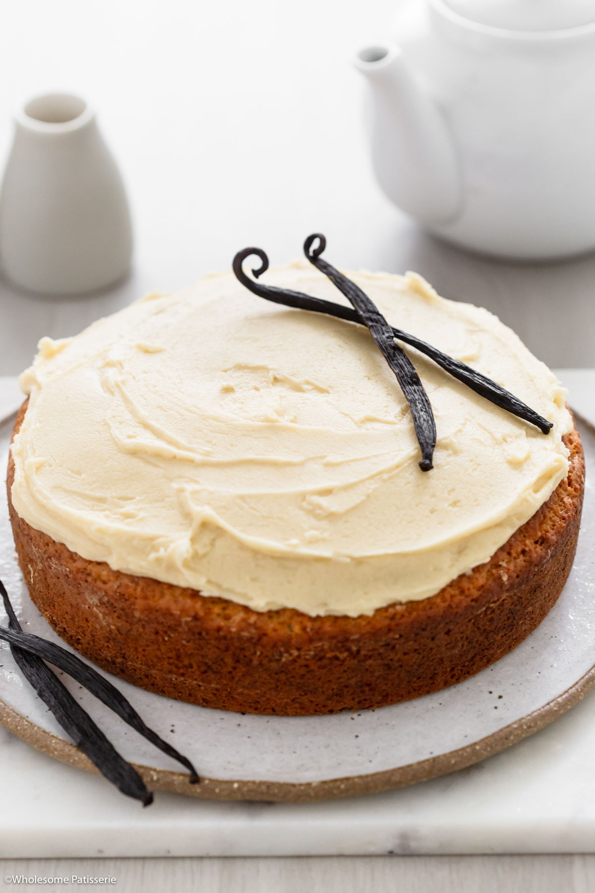 Eggless Vanilla Cake displayed on plate decorated with fresh vanilla bean pods