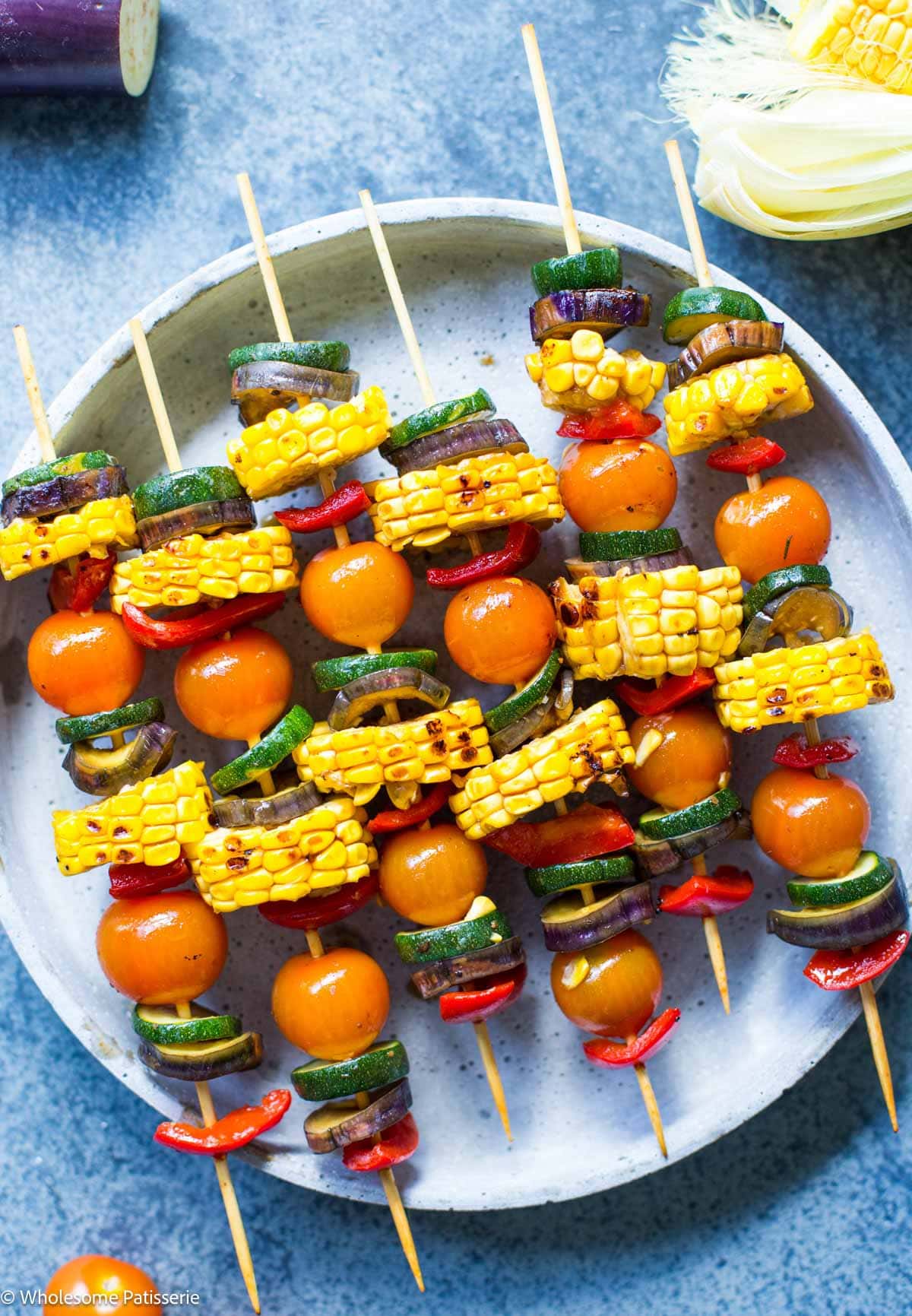 Vegetable BBQ skewers on wooden skewers arranged together on plate.