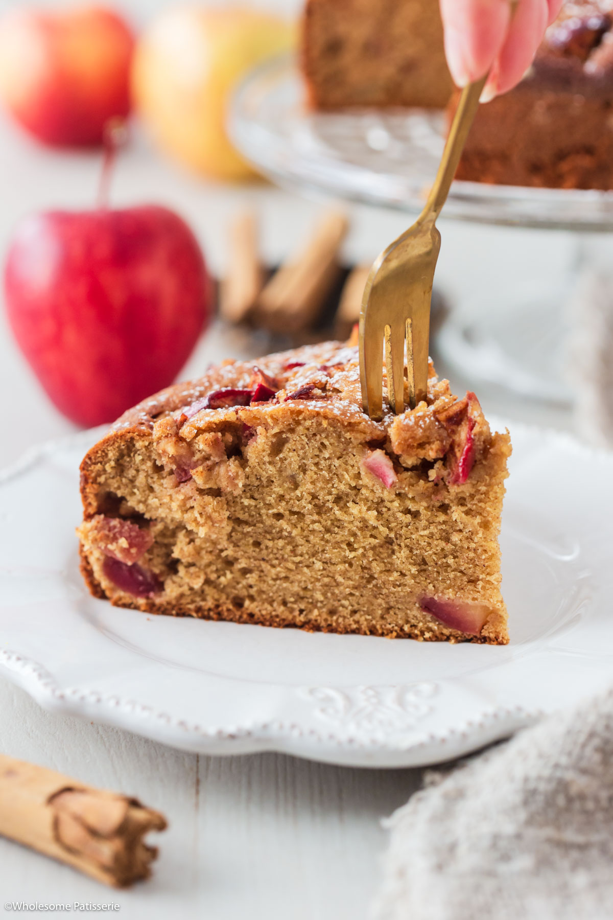 One slice of cinnamon apple cake with gold fork taking a bite out of it.