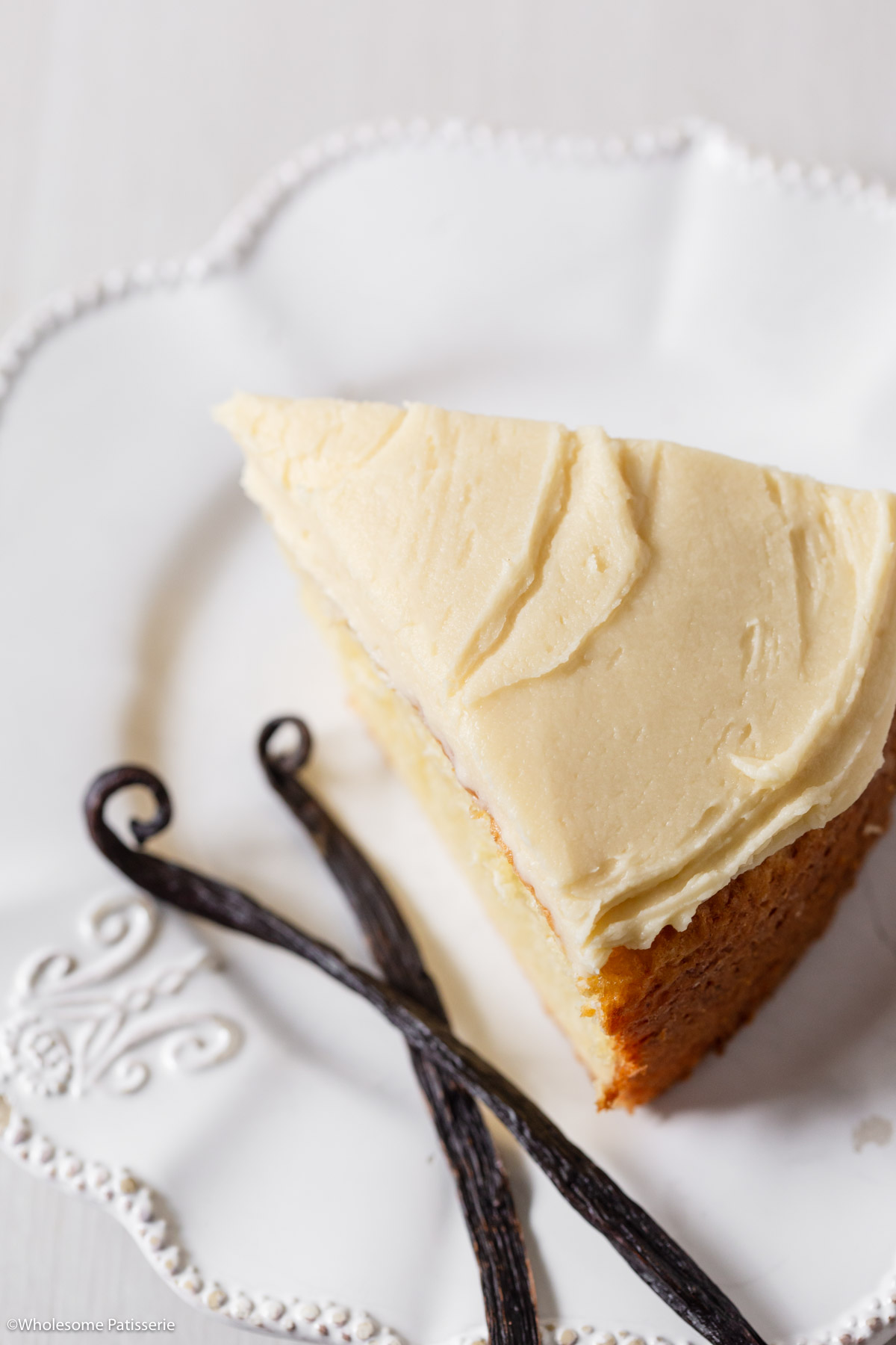 One slice of cake on plate with vanilla bean pods next to it