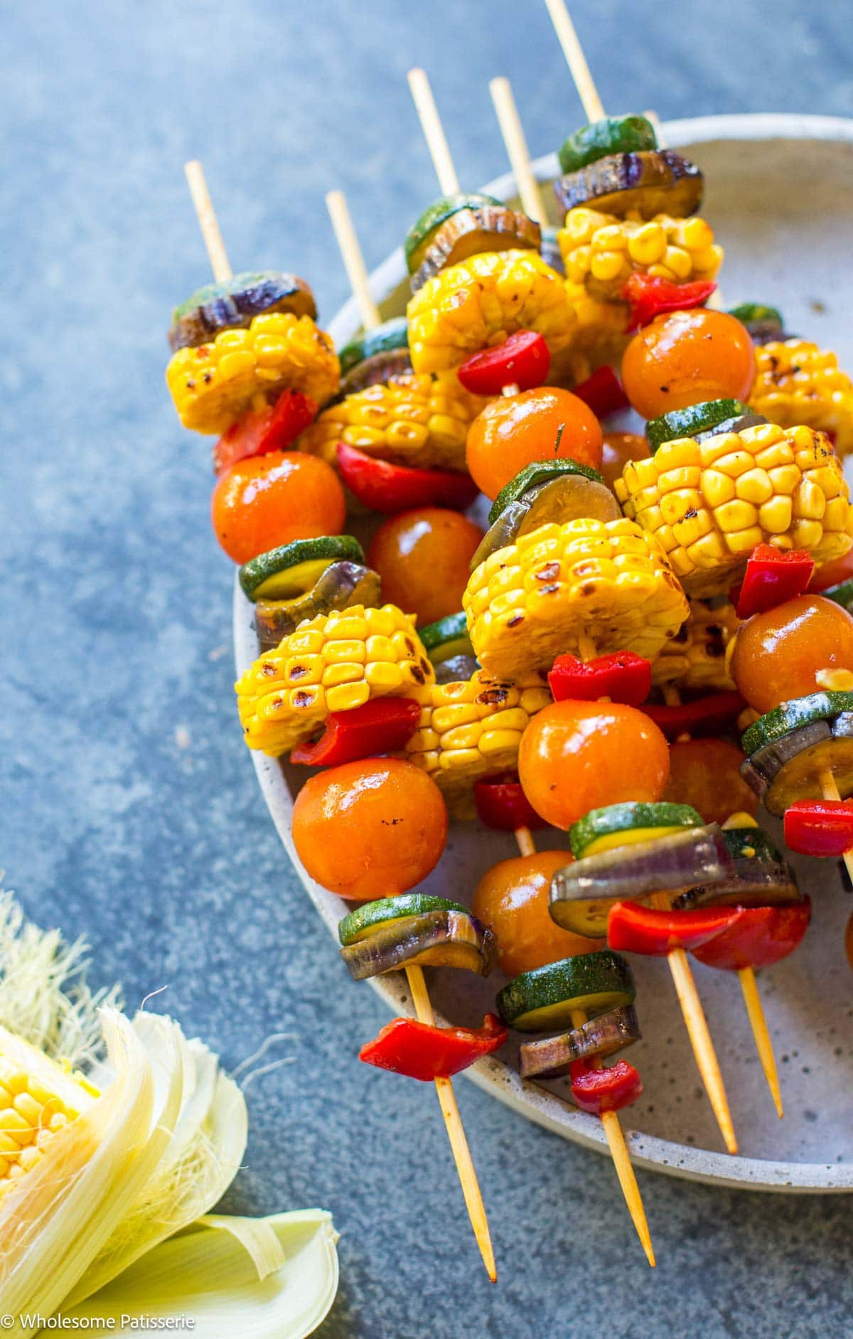 Close view of skewers on plate with corn in the corner.