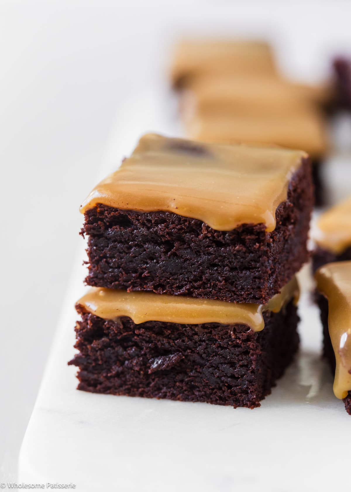 Two brownie squares sitting stacked together on marble platter.