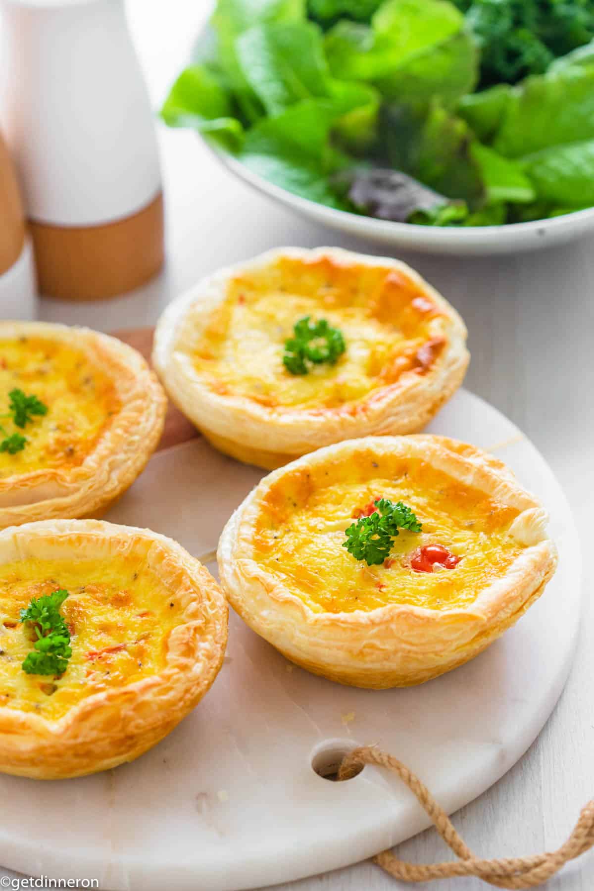 Individual quiches garnished with fresh parsley and sitting on marble platter.