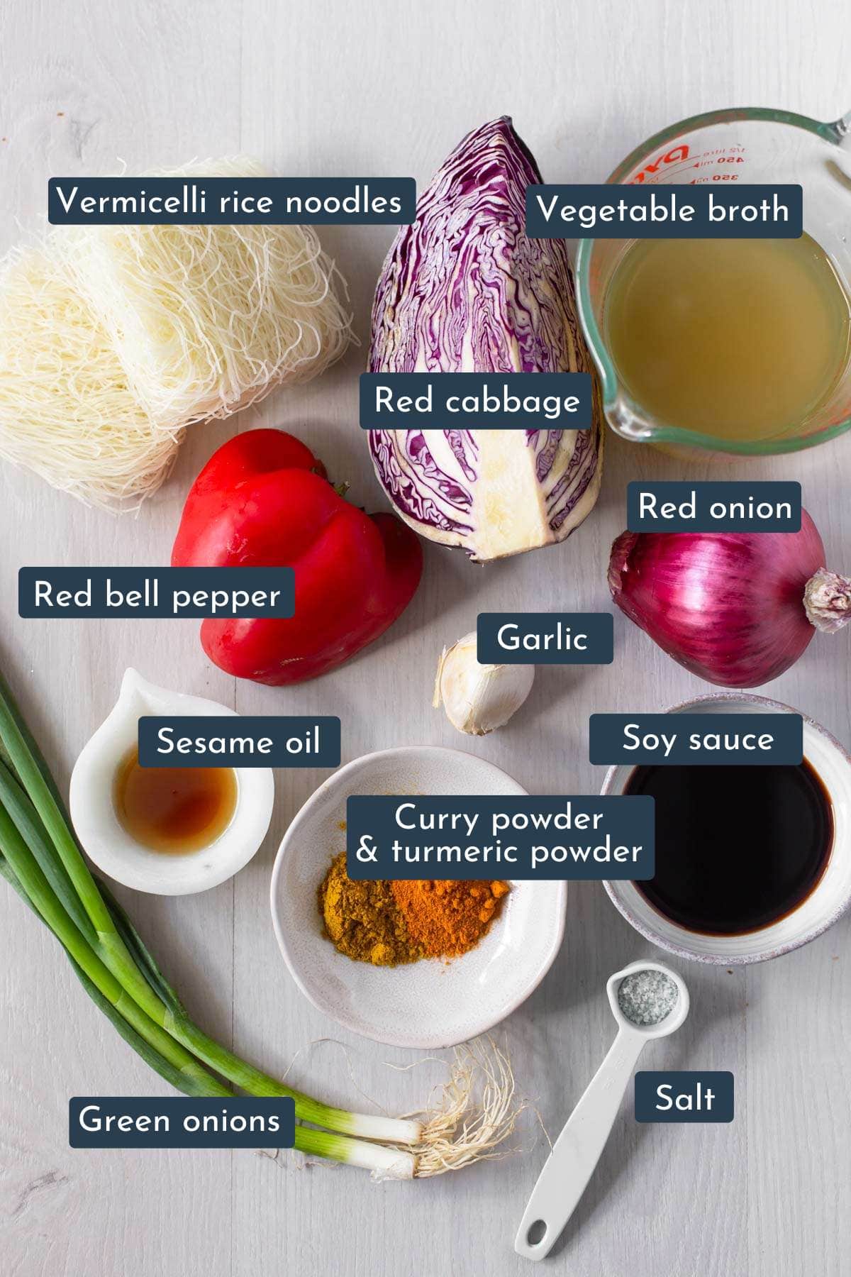 Ingredients to make vegetarian singapore noodles on white board.