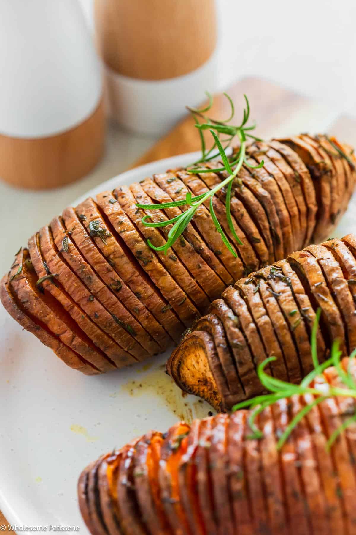 One sweet potato on plate next to more hasselback potatoes.