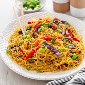 Vegetarian singapore noodles on plate with chopsticks.