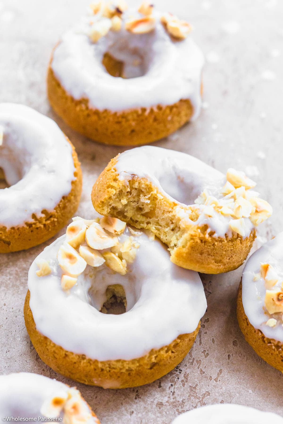 Baked coconut donuts sitting on beige background.