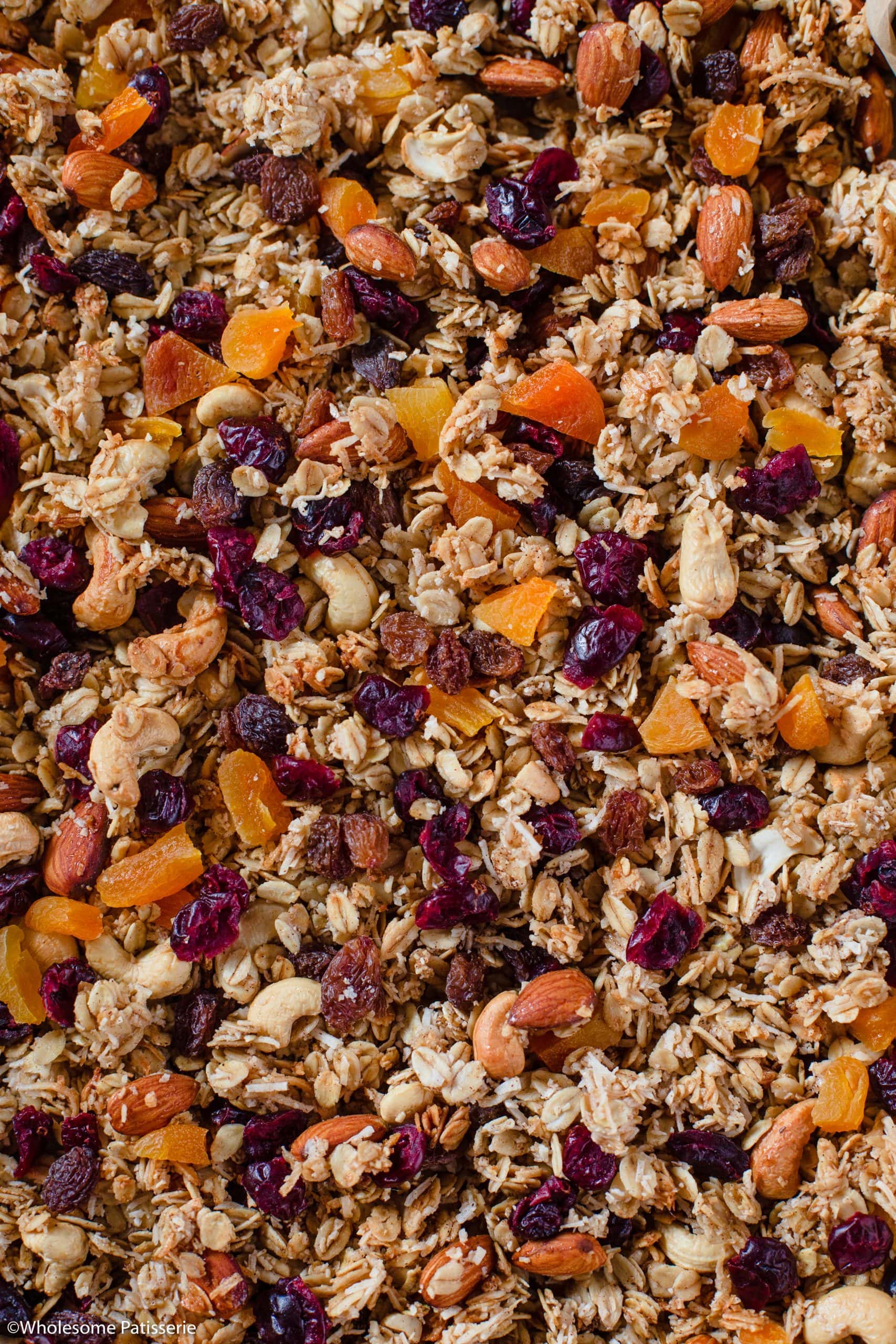 Fruit granola spread onto lined baking sheet and dried fruit stirred through.