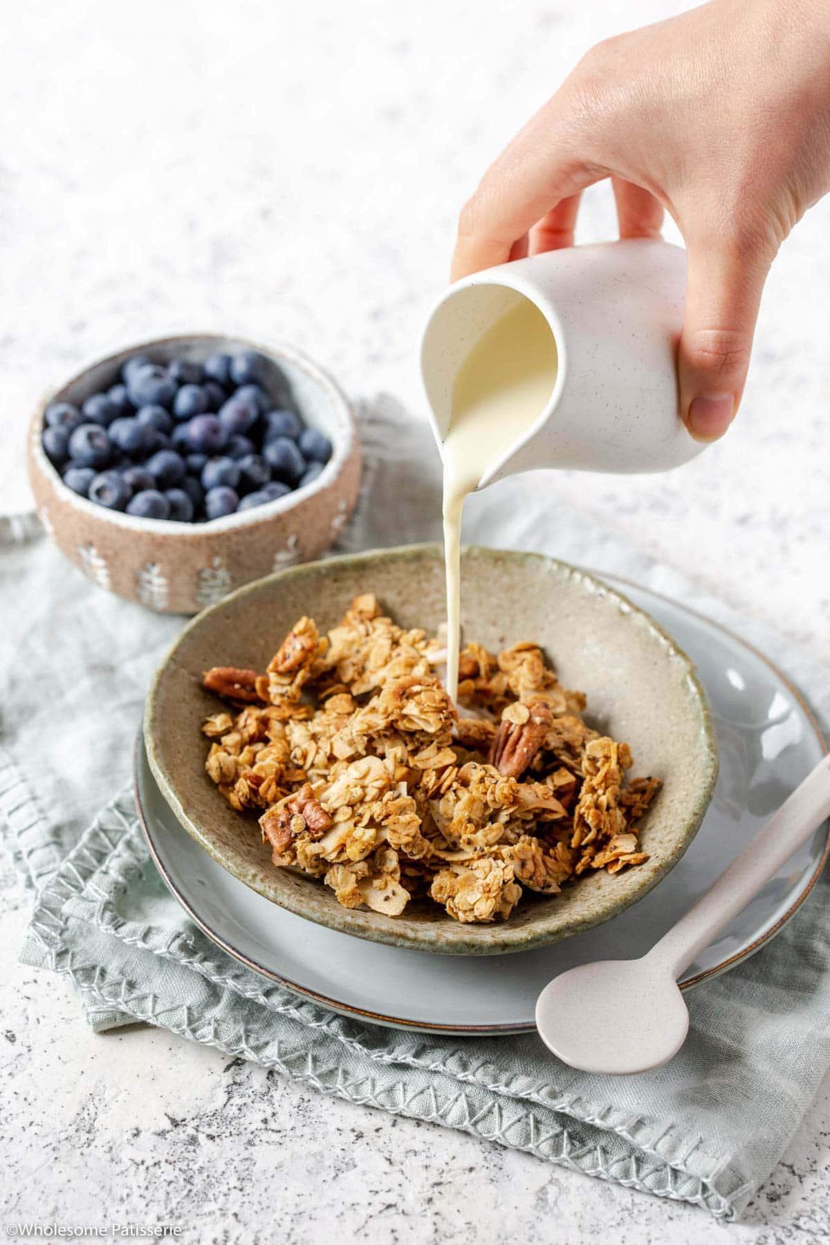 Easy chunky granola in cereal bowl with milk being poured in from jug.