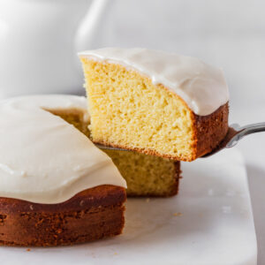 A slice of vanilla cake without butter being picked up with a cake cutter.