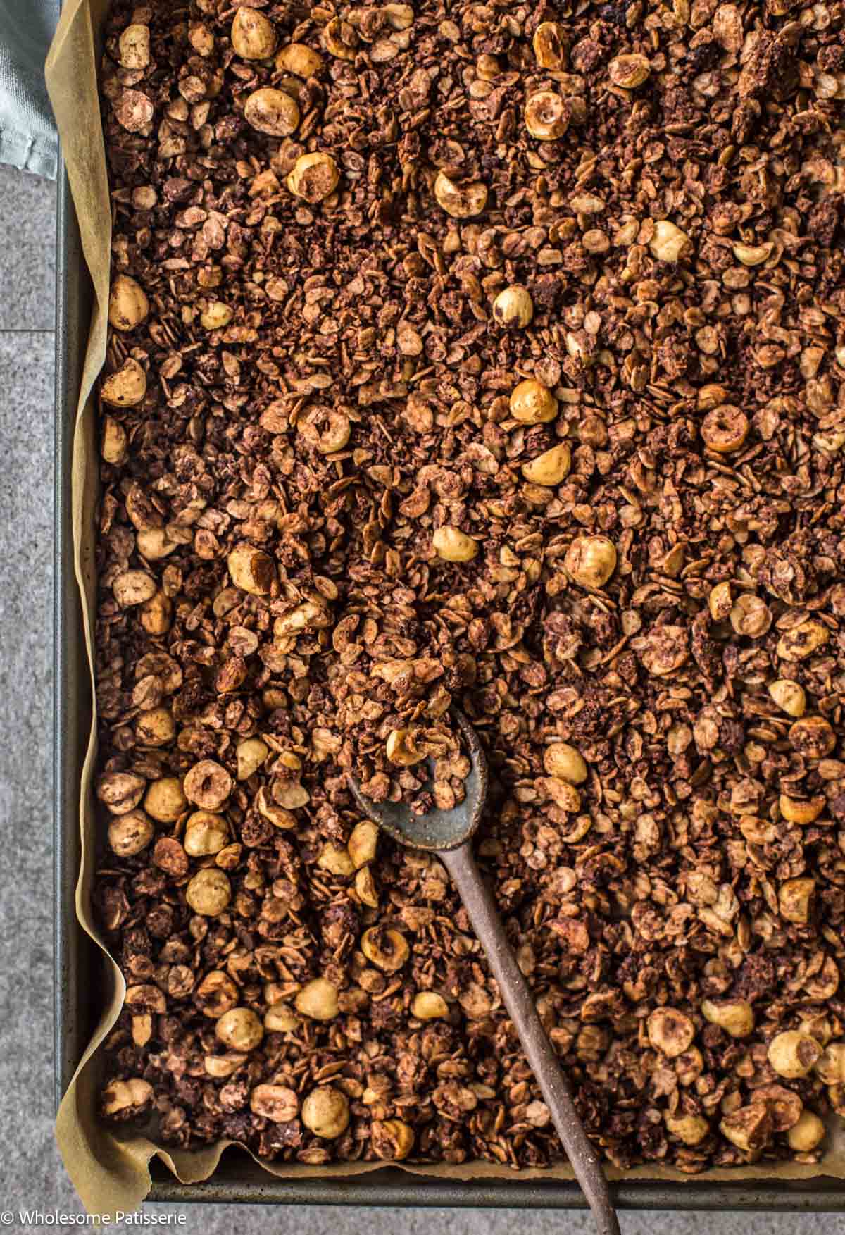Chocolate hazelnut granola baked and spread onto baking sheet.