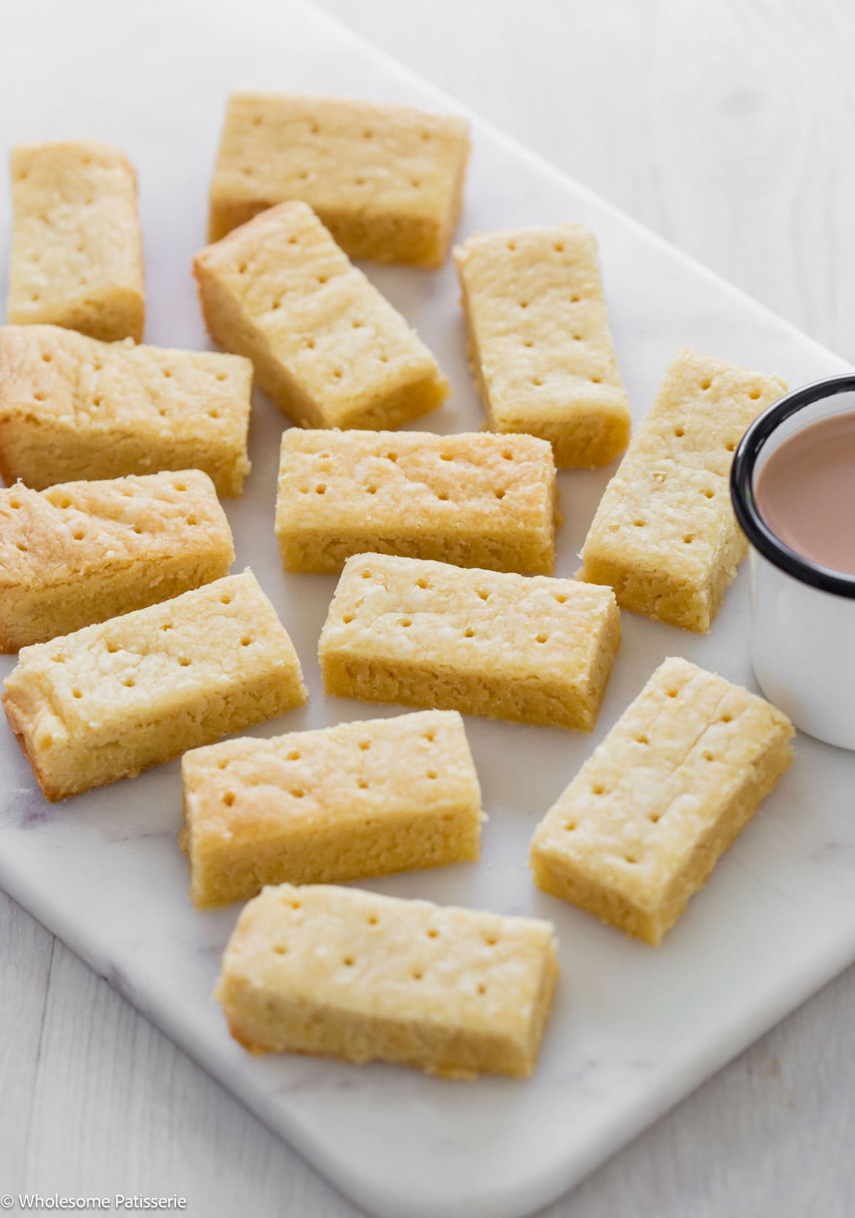 Easy shortbread cookies on white platter next to cup of tea.