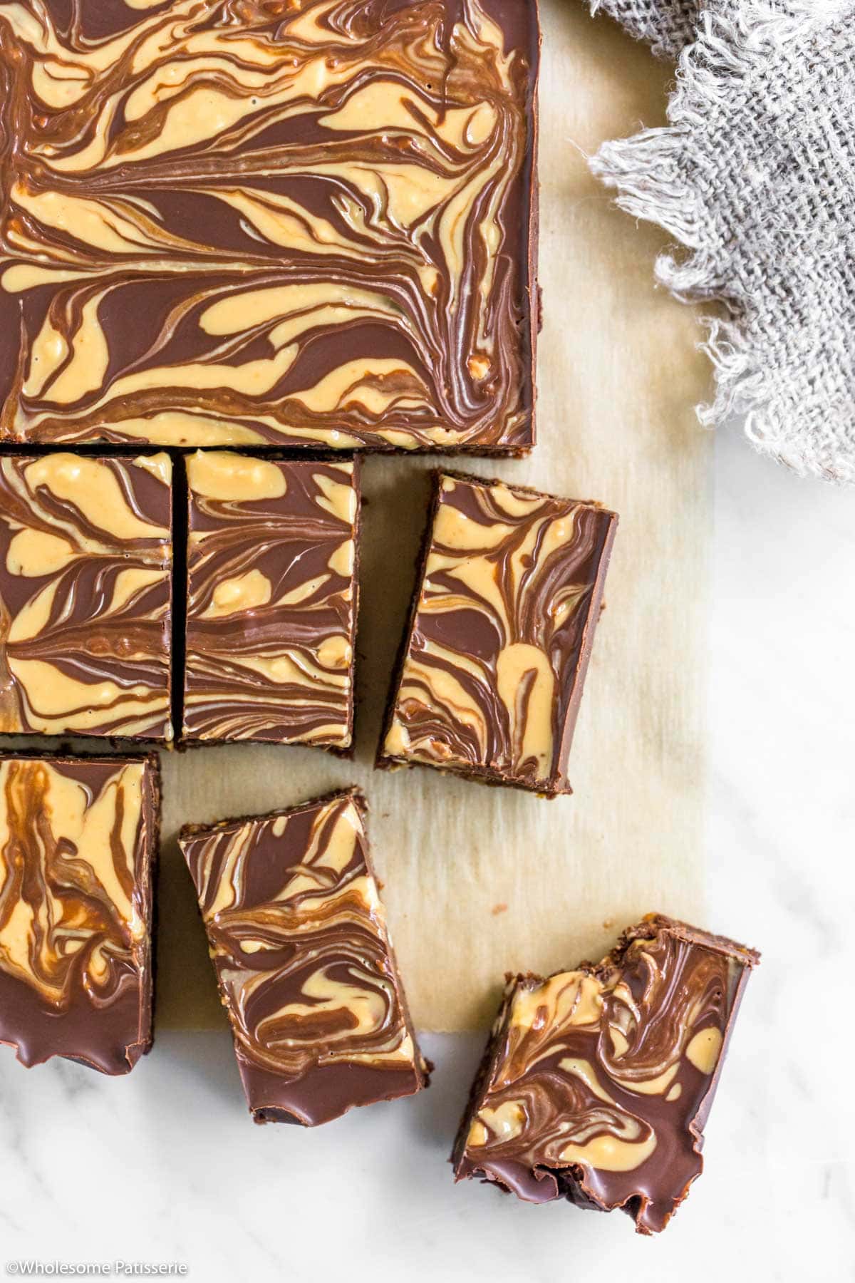 Peanut butter no bake brownies sliced and sitting on parchment paper lined board.
