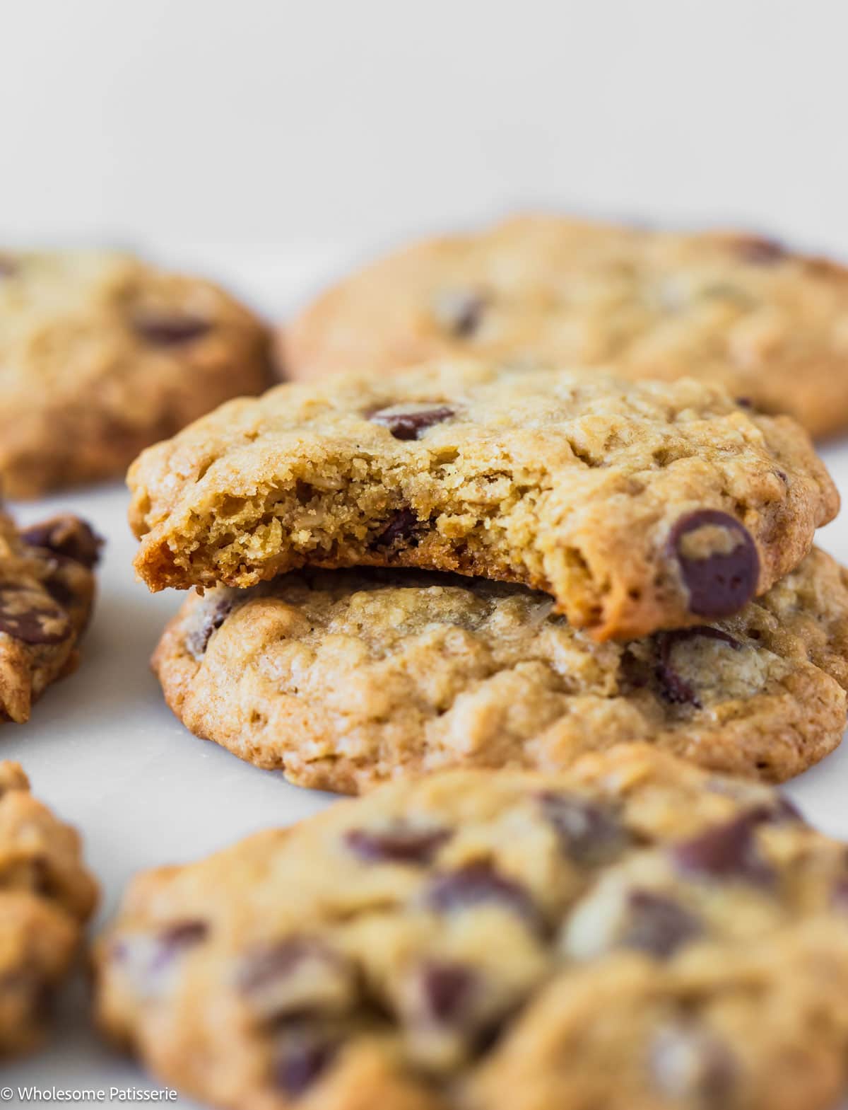 Two chocolate chip oatmeal cookies stacked together with the top cookie having a bite taken out.