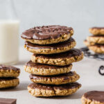 Chocolate wheatens made gluten free stacked in a tall cookie tower with more wheatens surrounding.