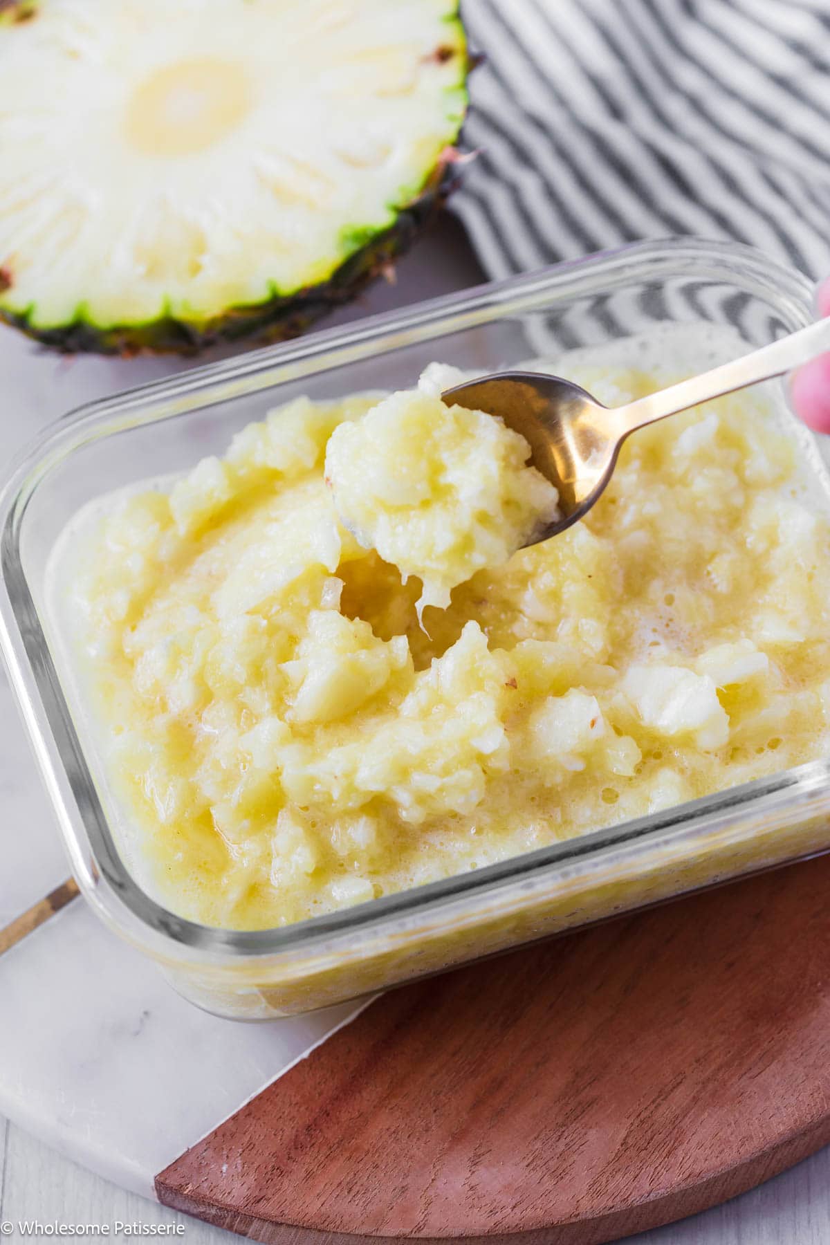 Scooping up homemade crushed pineapple from glass container.