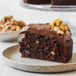 A slice of chocolate cake with walnuts on a plate.