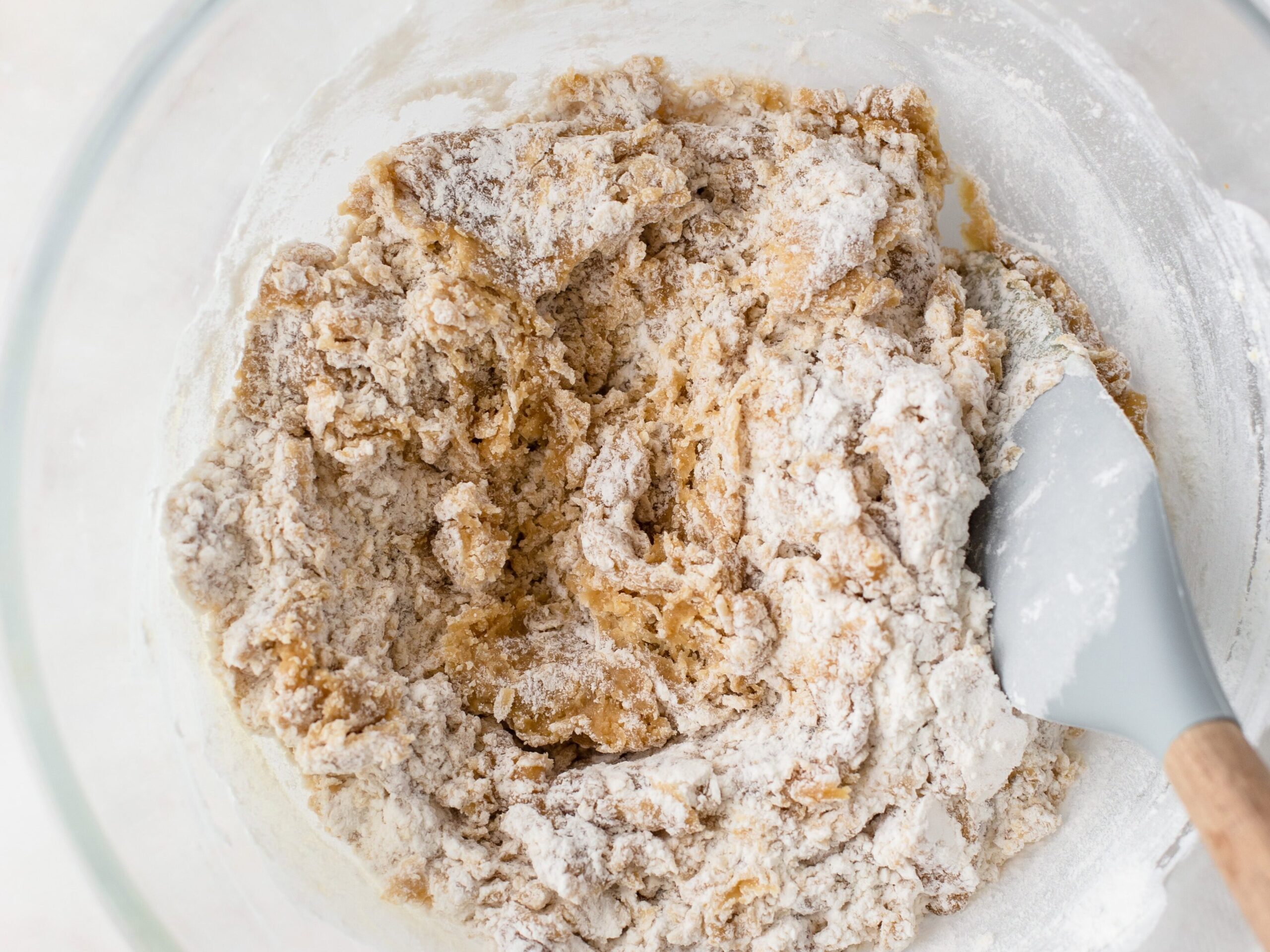 Flour mixed through cookie dough in bowl.