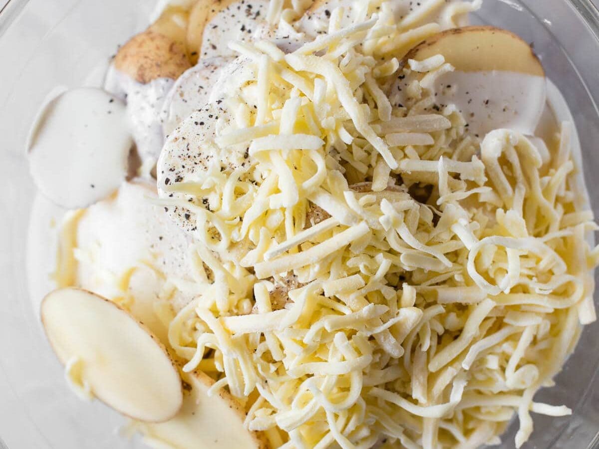 A bowl of potatoes with cheese, onions, and other ingredients.