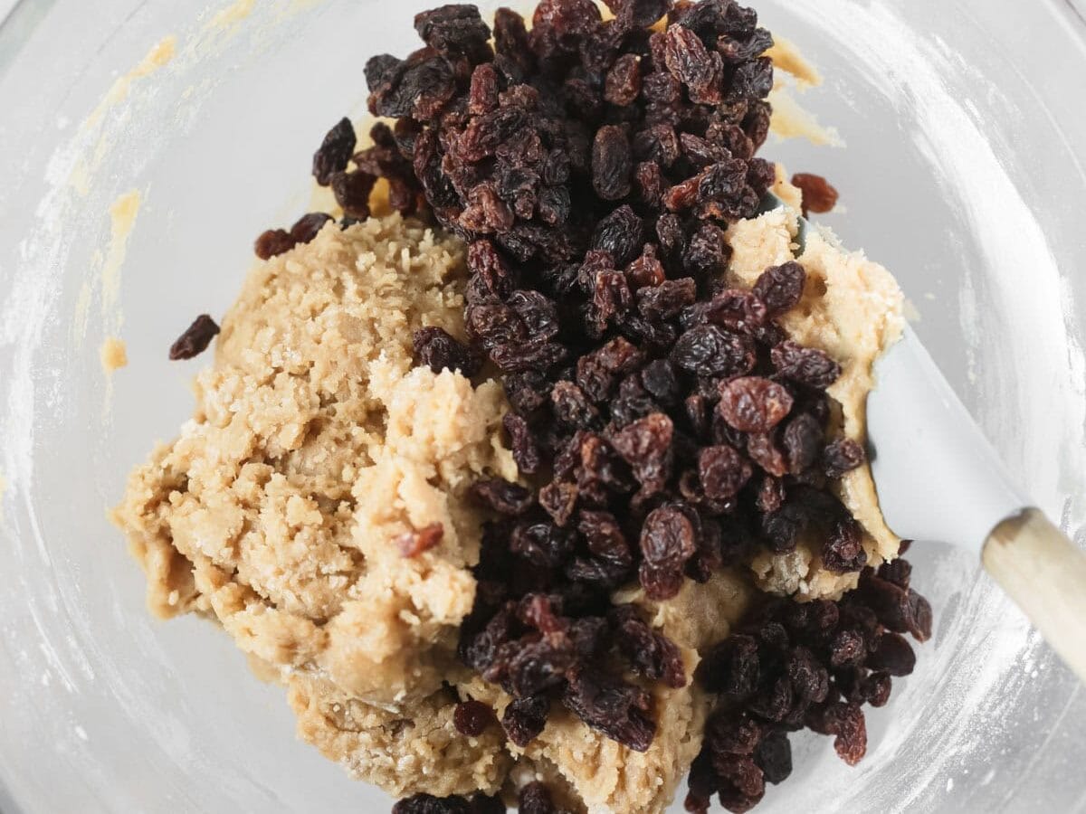 Sultanas being added to cookie dough.