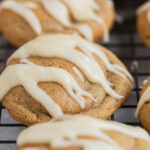 Chai latte cookies on cooling rack with milky drizzle.