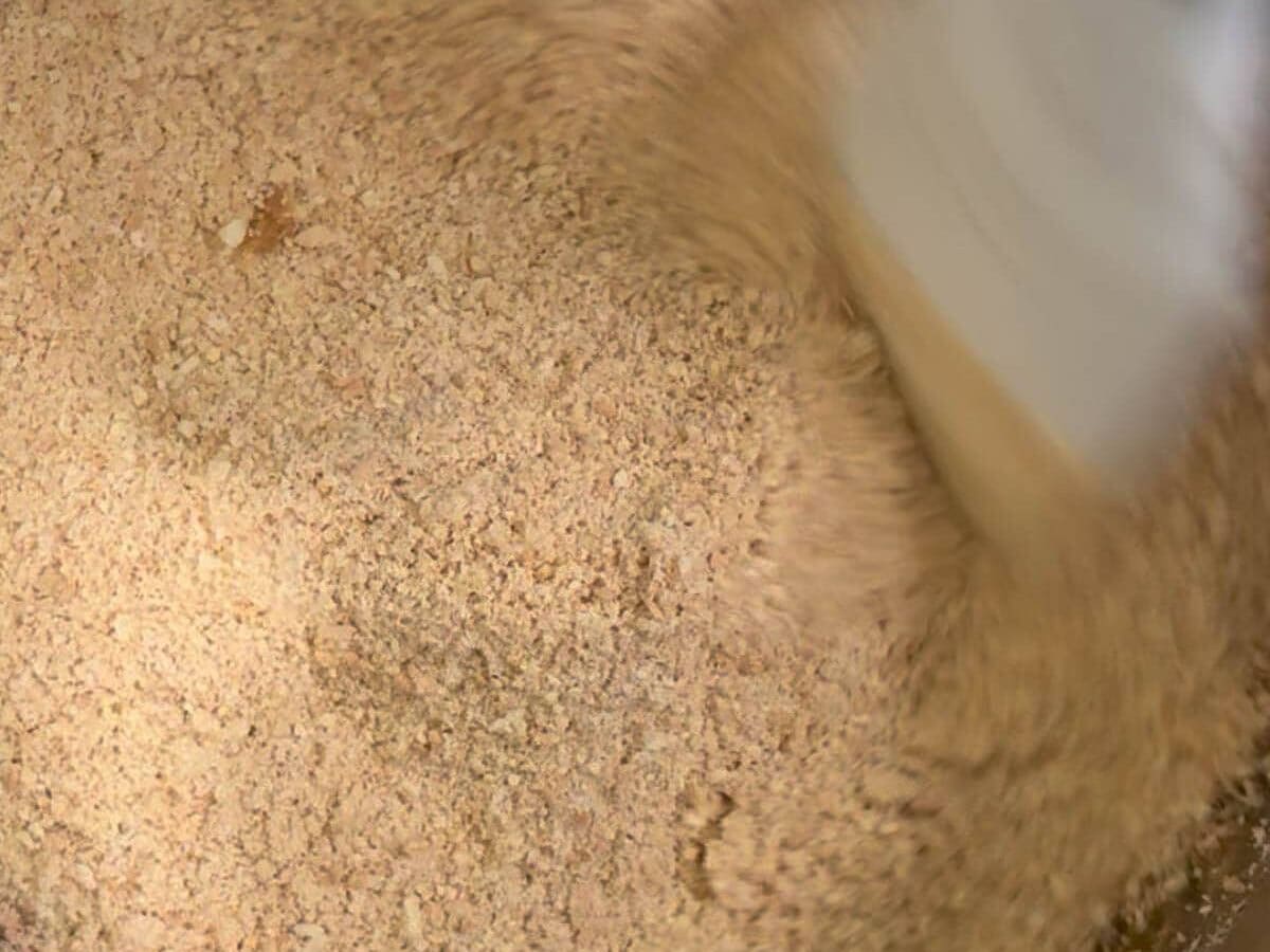 Mixing crushed biscuits into melted butter mixture.