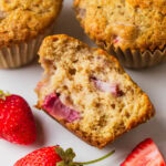 Bite taken out of one applesauce muffin with strawberries.